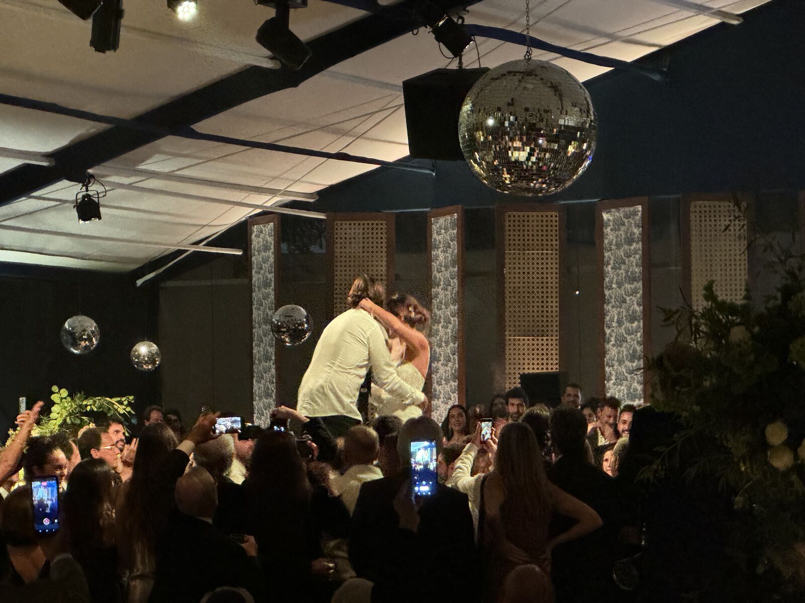 Momento de los novios en pista bajo el disco ball, rodeados por los invitados