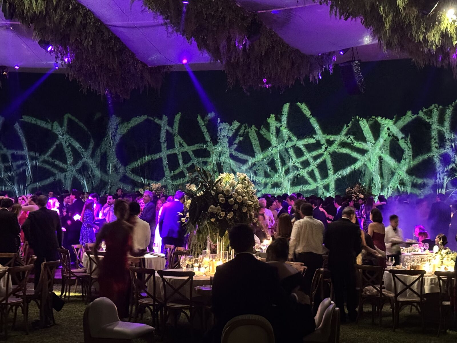 Salón con proyección verde y centros de mesa con flores